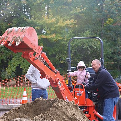 adult helping child operate digger